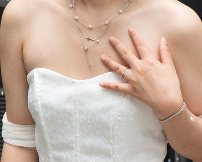 woman wearing dainty cross and pearl double layered silver necklace