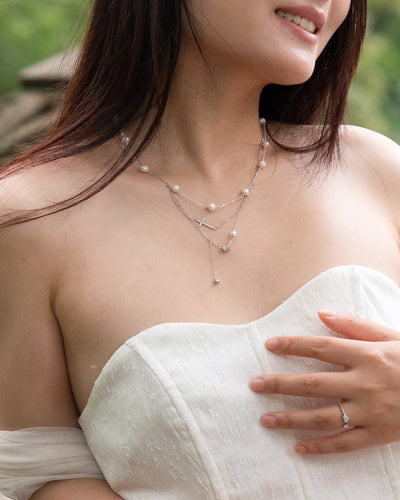 woman wearing dainty cross and pearl double layered silver necklace