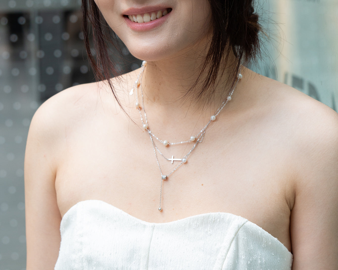 woman wearing dainty cross and pearl double layered silver necklace