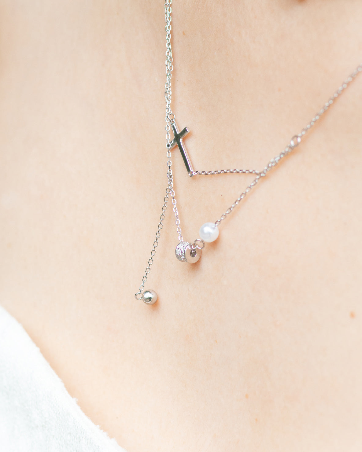 woman wearing dainty cross and pearl double layered silver necklace