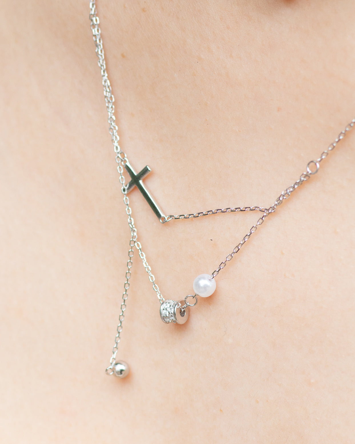 woman wearing dainty cross and pearl double layered silver necklace