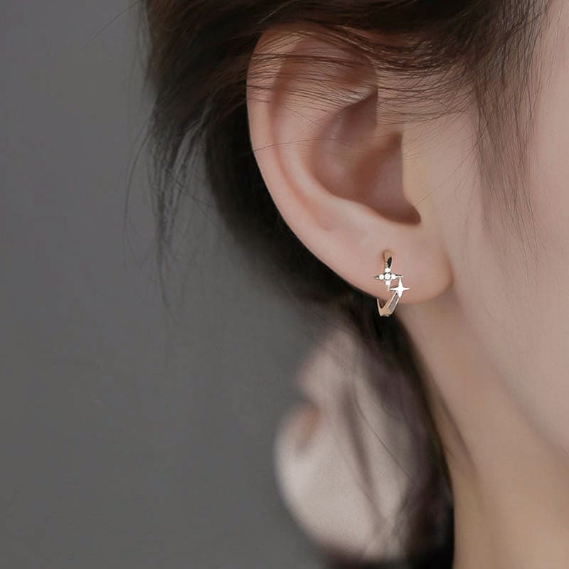 nolo woman wearing twinkle little star tiny cross dainty huggie gold cubic zirconia gemstone earrings