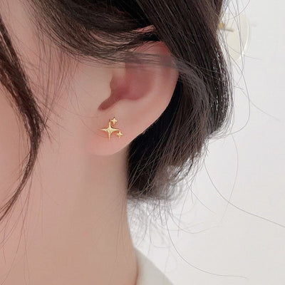 woman wearing nolo cute mini dainty four pointed multi star gold plated sterling silver stud earrings