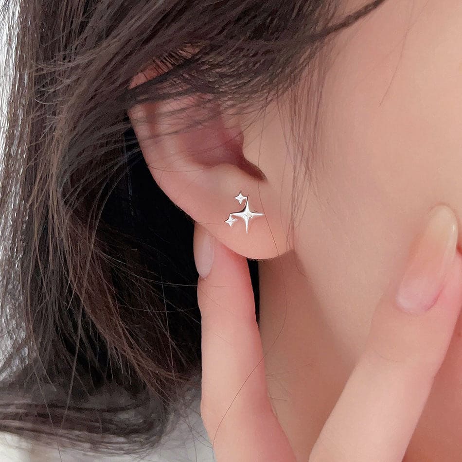 woman wearing nolo cute mini dainty four pointed multi star sterling silver stud earrings