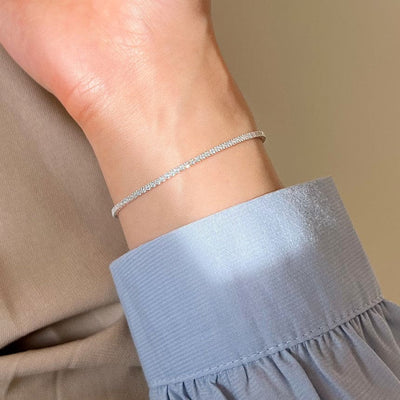 woman wearing nolo petite glimmer 1mm micro set sterling silver cubic zirconia gemstone dainty tennis bracelet