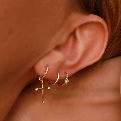 woman wearing 14K gold plated sterling silver huggie hoop cross zirconia drop earrings