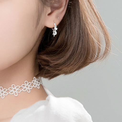 woman wearing cross moon and star huggie drop 925 sterling silver earrings