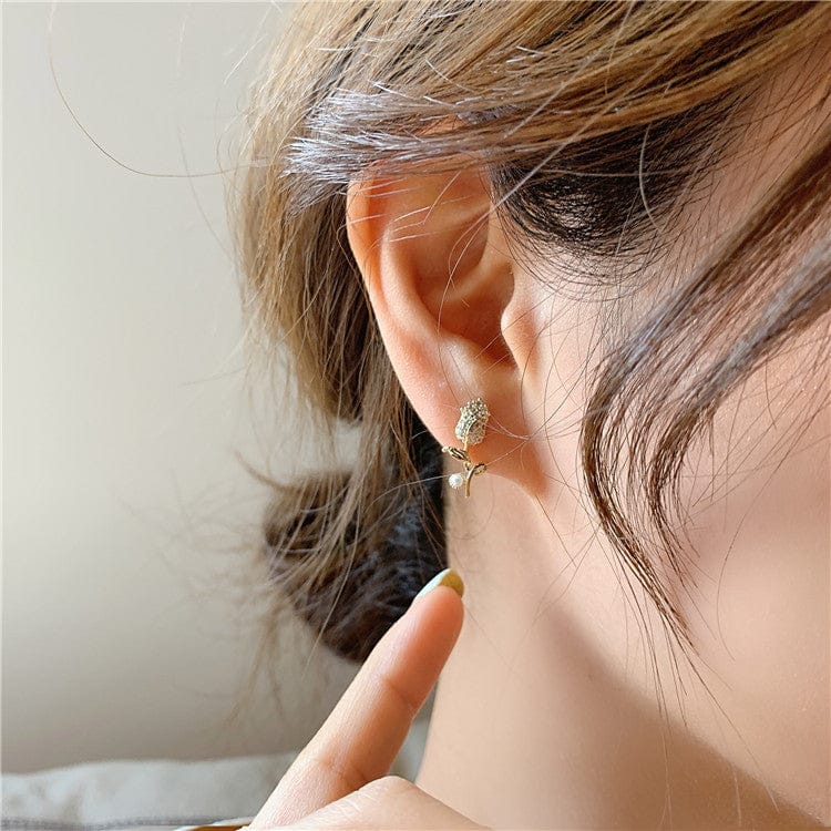 woman wearing nolo rosa de reina rose flower pearl gold colored fashion stud earrings